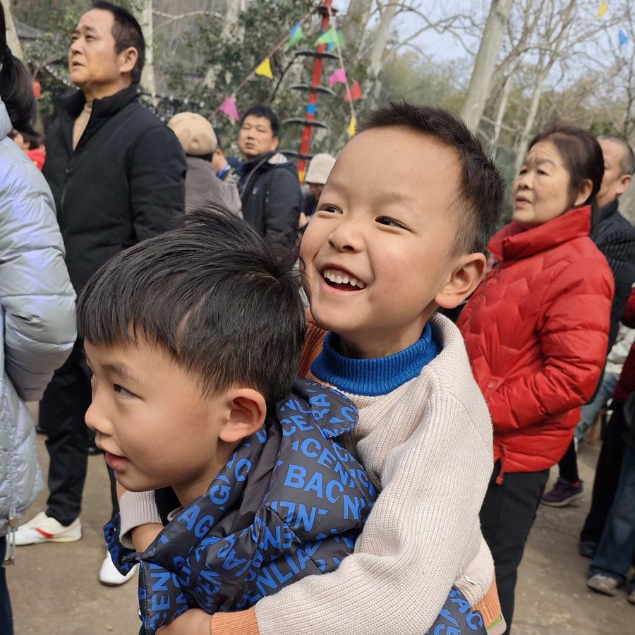 孩子趴在哥哥背上仰头大笑，笑容灿烂