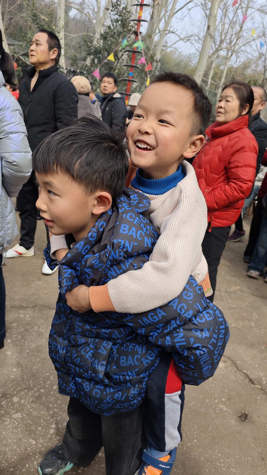 孩子趴在伙伴背上，仰头大笑，眼睛眯成一条线